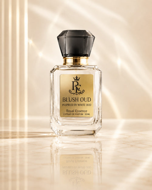 A 50ml bottle of Royal Essence Blush Oud Extrait de Parfum, featuring a clear glass body, a gold label with a black monogram logo, and a faceted black cap, set against a warm beige background with elegant light rays and a soft reflection.