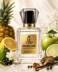 A clear glass perfume bottle labeled Imperial Noir Royal Essence, styled with fruit and flowers around it on a light surface. Visible ingredients include pineapple, lemon, lime, green apple, berries, bark, and vanilla beans.
