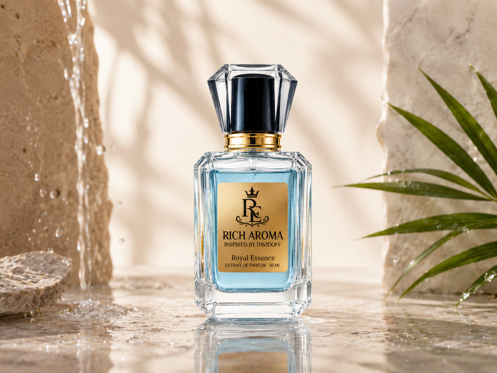 A bottle of Rich Aroma Royal Essence perfume stands on a reflective stone surface with water droplets, a stone wall, and a green palm leaf in the background. The bottle is clear glass with a light blue liquid inside, a gold label, and a faceted black cap with a gold collar.